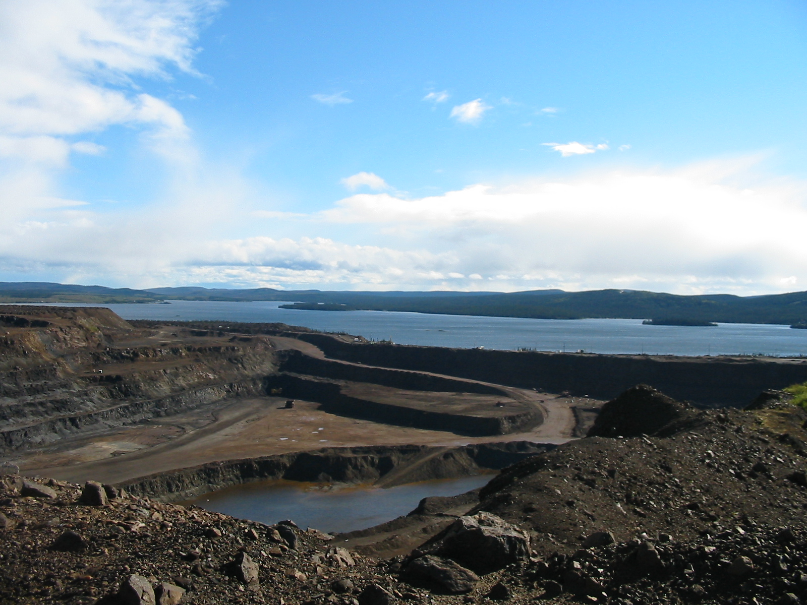 The Scully open pit mine at Wabush, with terraced rock walls descending to the pit floor and Wabush Lake visible in the background